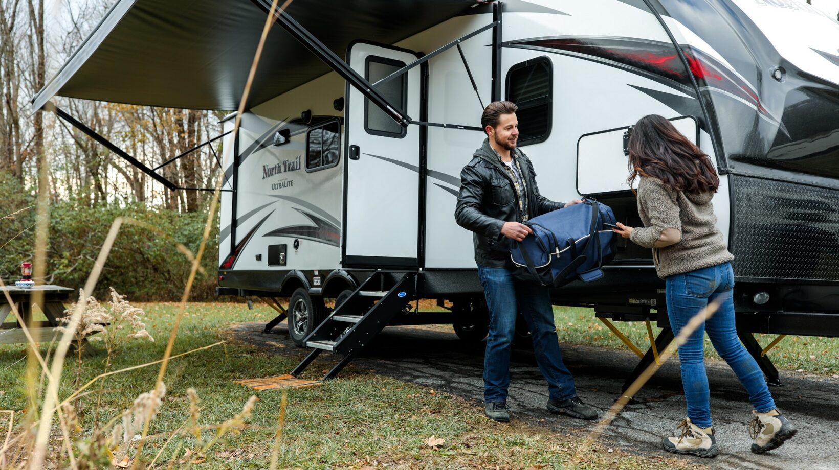Couple unloading a caravan with the awning already open.