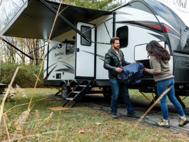 Couple unloading a caravan with the awning already open.