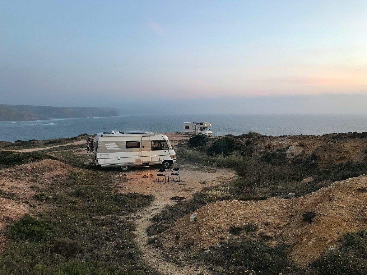 Caravan set up on a level surface next to a panoramic ocean view.