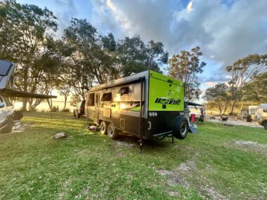 Caravan set up on an off-grid site with solar panels and battery systems providing power for appliances.