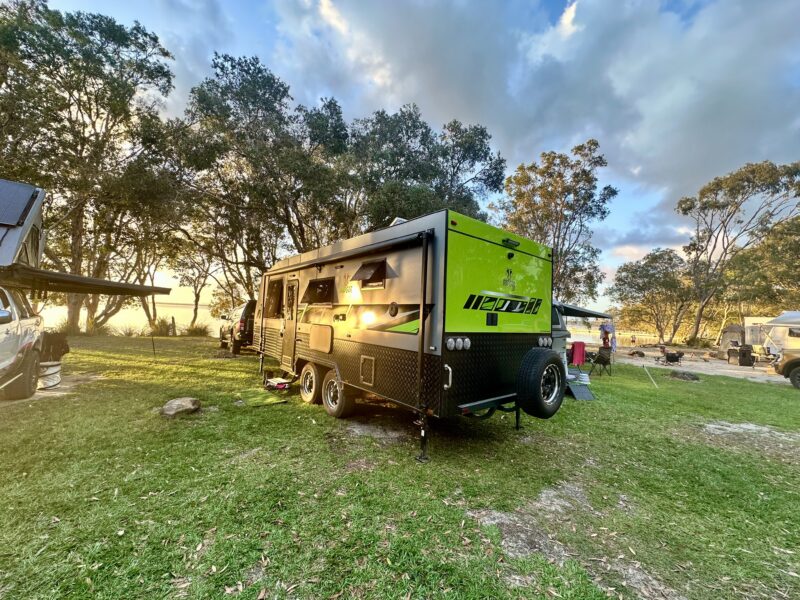 Caravan set up on an off-grid site with solar panels and battery systems providing power for appliances.